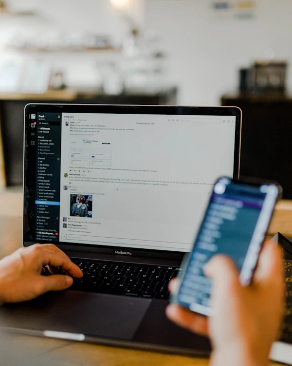 Chat app on a phone beside a laptop